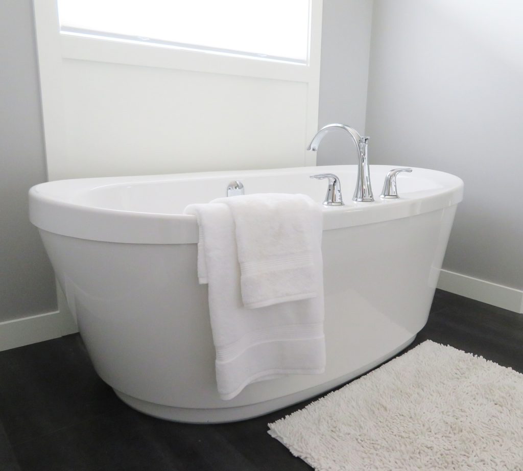 White freestanding bathtub with white towels draped over the side